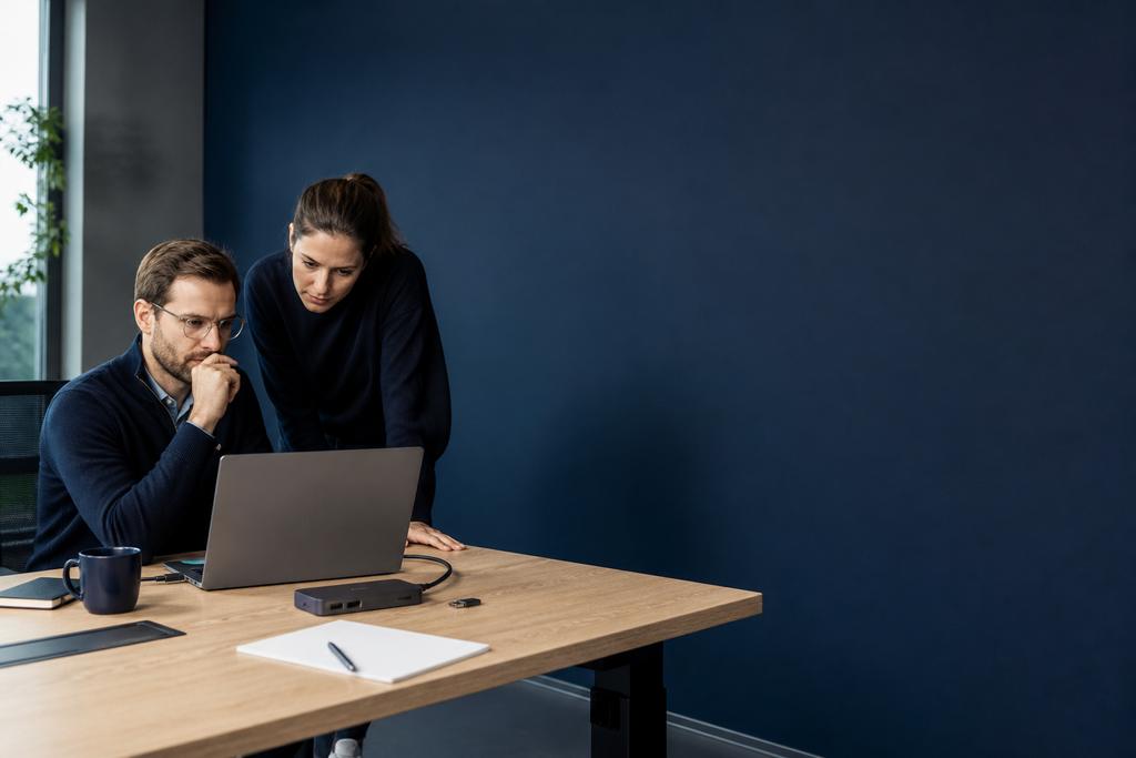 Illustratieve securityspecialist en endpointbeheerder die zakelijke laptop, beveiligingssleutel en verloren-apparaatprocedure beoordelen